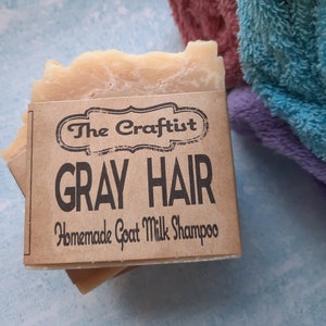 May include: A bar of handmade goat milk shampoo labeled "The Craftist Gray Hair Homemade Goat Milk Shampoo".