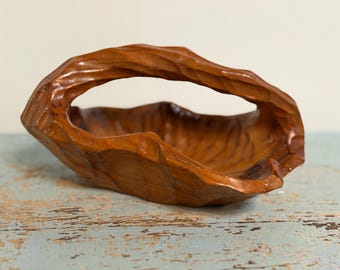 Cesta antigua de arte popular tallada en una sola pieza de madera de nogal negro, con asa naturalista y forma ovalada.