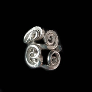 Op de afbeelding: Een zilveren ring met een draaiend, abstract ontwerp.