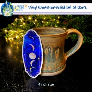 May include: A vinyl weather-resistant sticker featuring a moon phase design on a blue background with gold stars. The sticker is 4 inches in size and is shown on a ceramic mug.