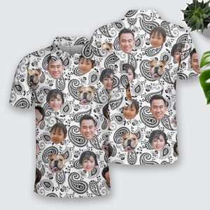 May include: White short-sleeved button-up shirt with a paisley pattern. The pattern features various faces of people and dogs.