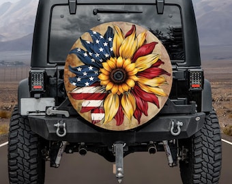 May include: A spare wheel cover with a sunflower design incorporating the American flag. The design features blue with white stars, red and white stripes, and yellow and red petals. The cover is mounted on a black Jeep.