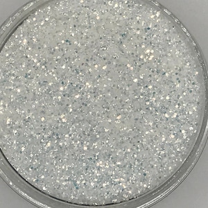 May include: A close-up view of a small jar filled with iridescent white glitter.