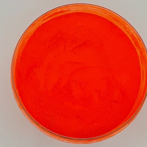 Puede incluir: Un pequeño recipiente de plástico transparente lleno de polvo naranja brillante.