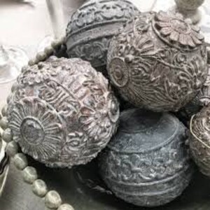 Puede incluir: Cinco esferas decorativas con intrincados dise&ntilde;os en relieve en tonos grises y marrones. Las esferas est&aacute;n dispuestas en un cuenco.