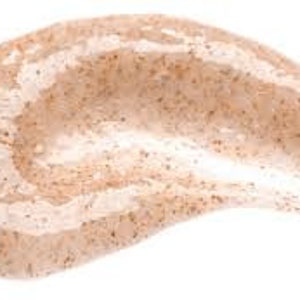 May include: Close-up of a light brown scrub with small exfoliating particles. The scrub has a smooth, gel-like consistency.