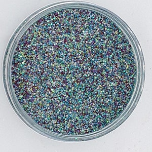 Può includere: Un barattolo trasparente pieno di glitter iridescenti blu, verdi e viola.
