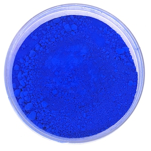 May include: A small, clear container filled with a bright blue powder. The powder is finely ground and has a uniform texture.