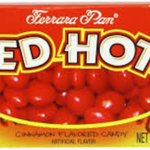 Peut inclure: Une boîte rouge de bonbons Red Hots à la cannelle. La boîte est étiquetée "A Fat Free Food" et "Ferrara Pan". Le poids net est de 0,9 oz (25,5 g).