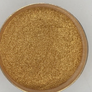 May include: A close-up of a small container filled with gold glitter.