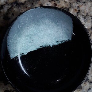 K&ouml;nnte beinhalten: Eine schwarze Sch&uuml;ssel mit einer hellblauen Glasur auf der oberen H&auml;lfte. Die Sch&uuml;ssel ist rund und hat eine glatte Oberfl&auml;che.
