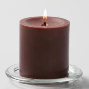May include: A brown pillar candle on a clear glass plate. The candle is unlit.