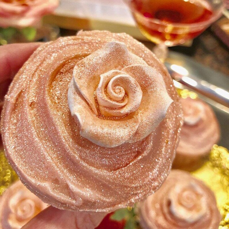 Peut inclure: Gros plan sur un cupcake rose avec un gla&ccedil;age en forme de rose. Le gla&ccedil;age est recouvert de paillettes comestibles.