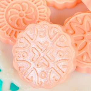 Peut inclure: Gros plan sur quatre bombes de bain roses et blanches avec des motifs d&eacute;coratifs. Les bombes de bain sont rondes et ont une surface lisse et brillante.