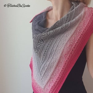 May include: A triangular shawl with a gradient of grey, white, and pink. The shawl is knitted with a delicate lace pattern.