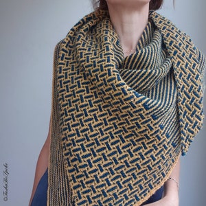 Pode incluir: Um xale de malha amarelo e azul com um padr&atilde;o geom&eacute;trico. O xale est&aacute; drapeado em volta do pesco&ccedil;o e dos ombros de uma pessoa.
