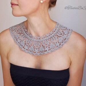 May include: A gray crocheted collar necklace with a delicate floral pattern.