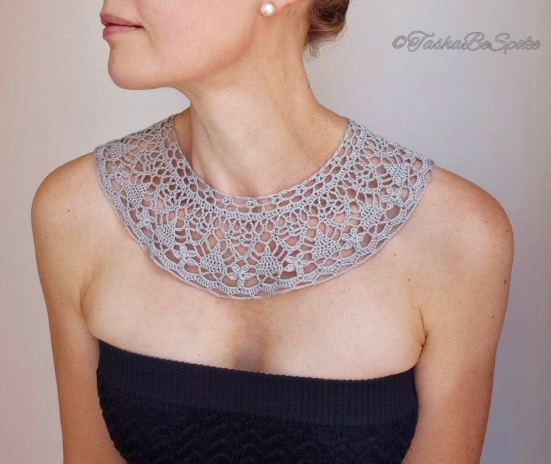 May include: A gray crocheted collar necklace with a delicate floral pattern.