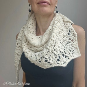 May include: A white crocheted shawl with a delicate lace pattern. The shawl is draped around a person's neck and shoulders.