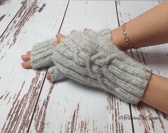 May include: Gray fingerless gloves with a cable knit pattern. The gloves are made of a soft, fuzzy yarn.