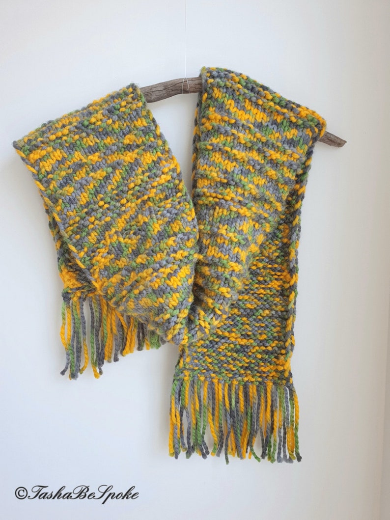 May include: A hand-knitted scarf in shades of yellow, green, and gray with fringe on the ends.