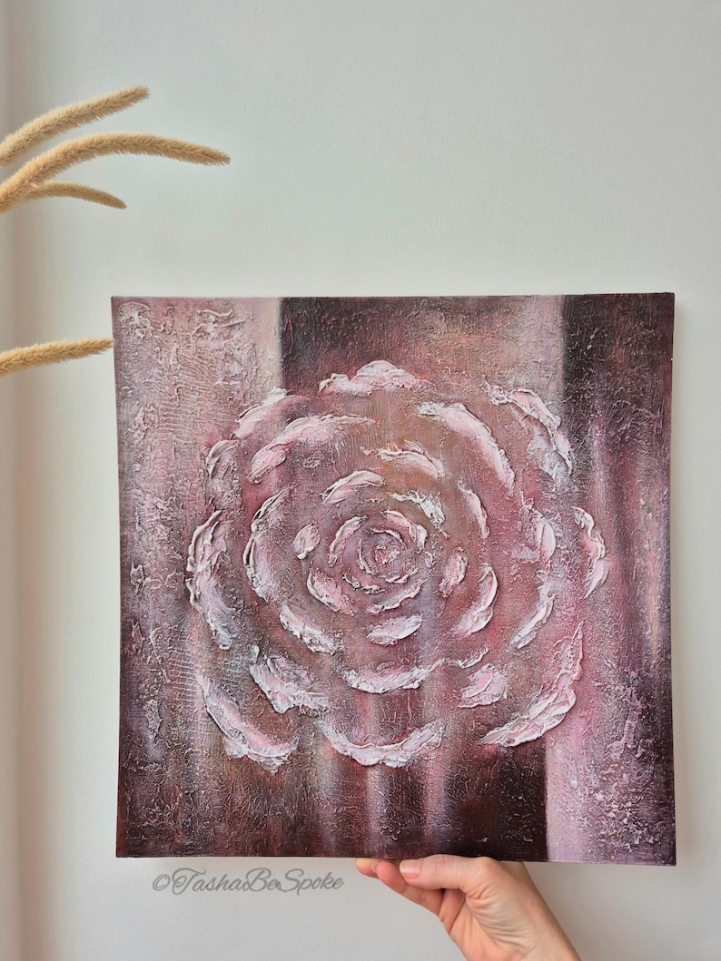 May include: A square canvas artwork depicting a textured rose in shades of pink and white, set against a textured, dark burgundy backdrop. The artist's signature, "TashaBeSpoke", is visible. The piece is a floral-themed artwork.