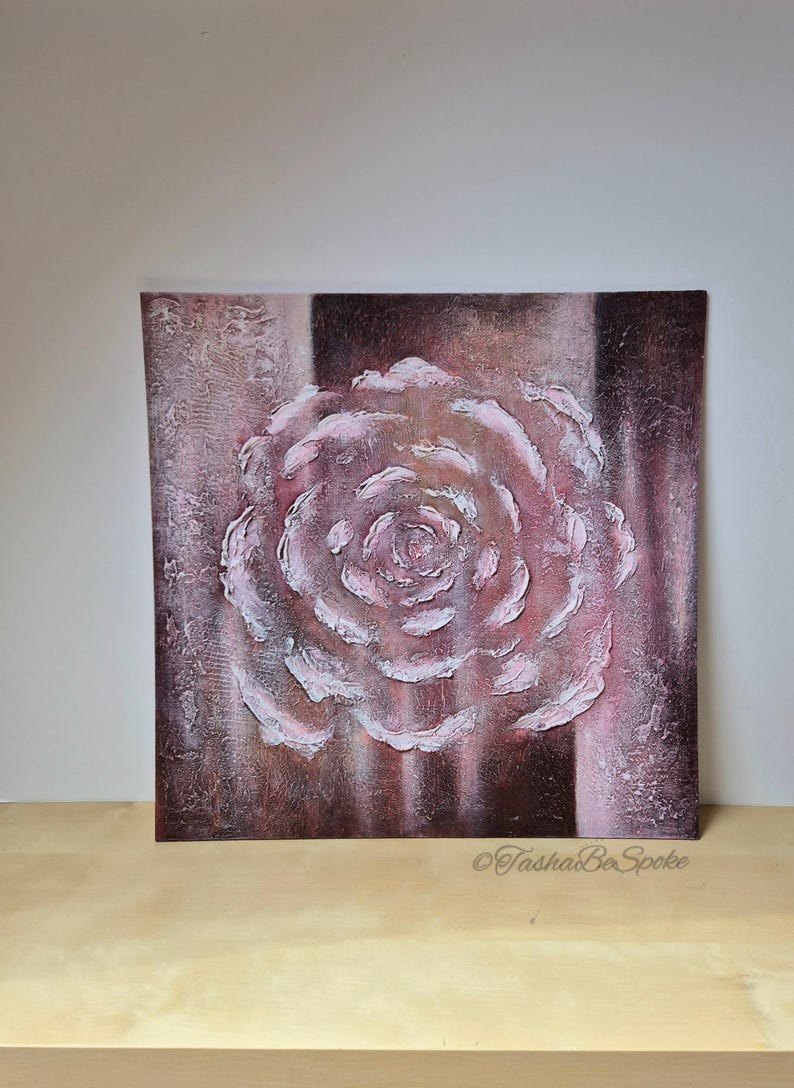 May include: A square canvas artwork depicting a textured rose in relief, in shades of pink and white. The background features vertical stripes of brown and pink. The artist's signature, "TashaBeSpoke", is visible in the lower right corner.