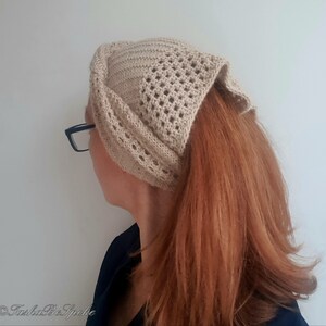 Puede incluir: Una diadema de crochet beige con un patr&oacute;n de encaje. La diadema la lleva una persona con el pelo largo y rojo.