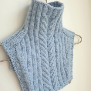 May include: A light blue knitted turtleneck collar with a cable knit pattern.