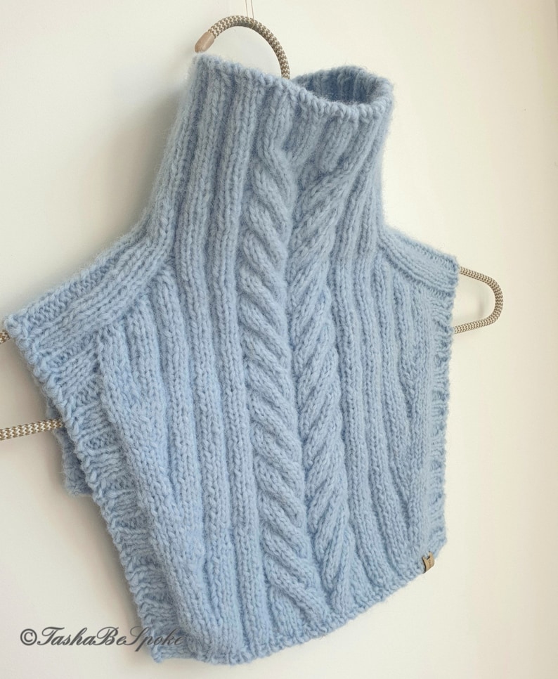 May include: A light blue knitted turtleneck collar with a cable knit pattern.