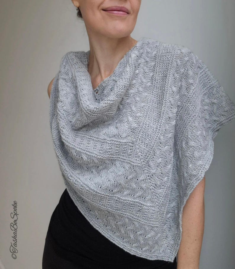 May include: A gray knitted shawl with a cowl neck and a cable knit pattern.