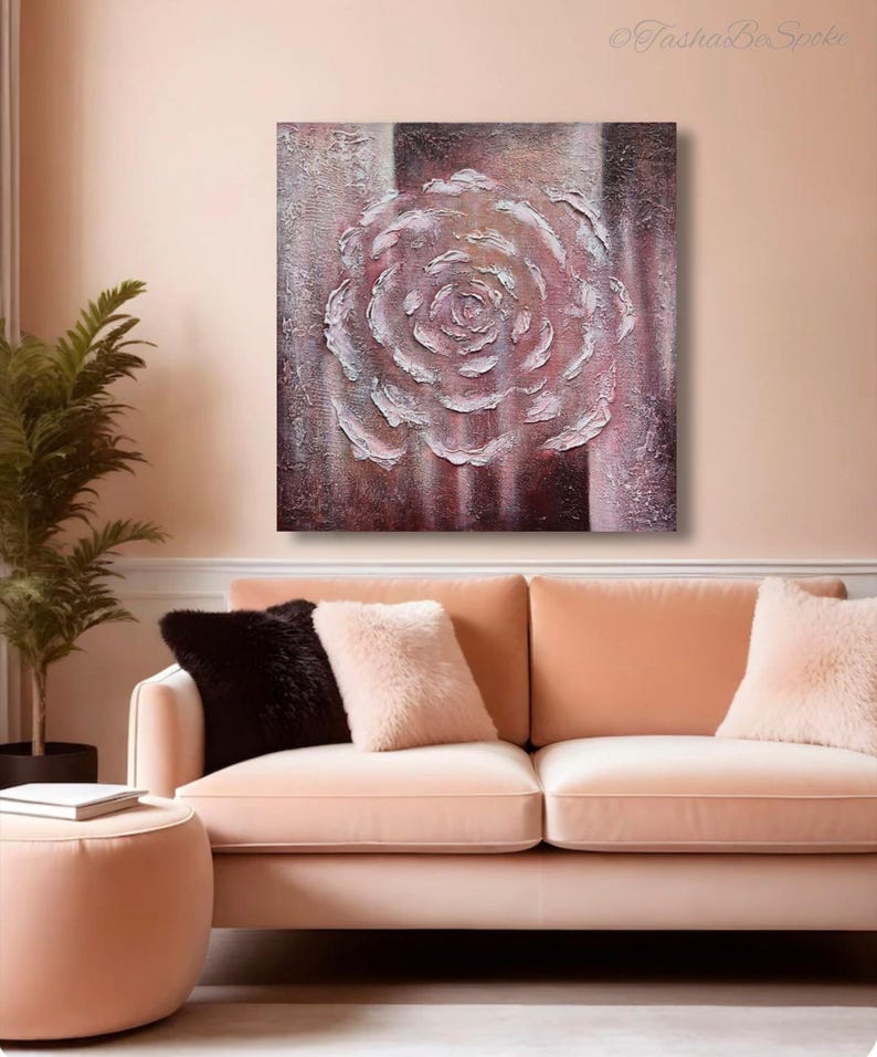 May include: A textured painting of a white rose on a canvas with a striped background of burgundy and cream. The artwork hangs above a peach-coloured sofa with decorative cushions. The room has a warm, inviting atmosphere.