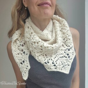May include: A white crocheted shawl with a delicate lace pattern. The shawl is draped around a person's neck and shoulders.