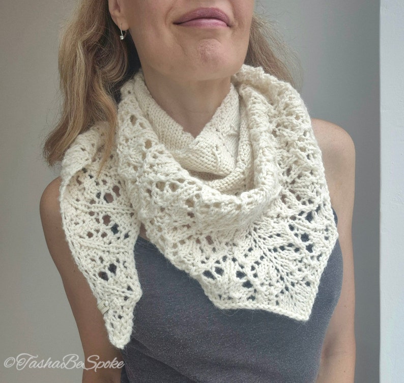 May include: A white crocheted shawl with a delicate lace pattern. The shawl is draped around a person's neck and shoulders.