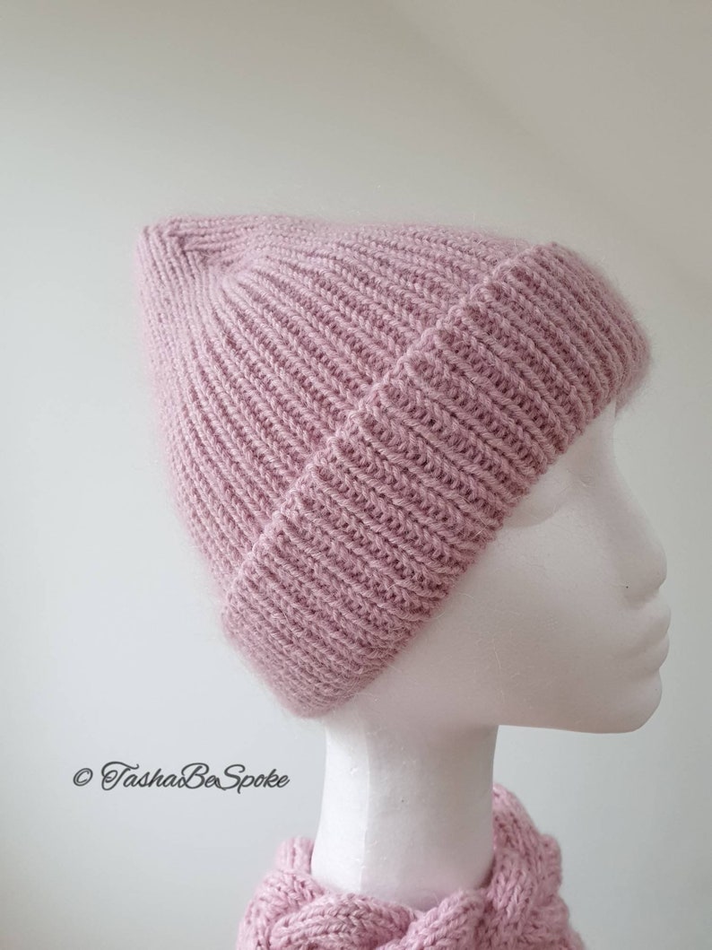 K&ouml;nnte beinhalten: Eine rosa gestrickte M&uuml;tze mit Rippenstruktur. Die M&uuml;tze sitzt auf einem wei&szlig;en Mannequin-Kopf.