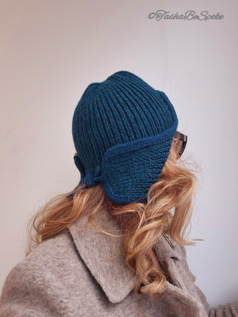 K&ouml;nnte beinhalten: Eine tealblaue Strickm&uuml;tze mit umgeschlagenem Rand und einem einzigartigen Ohrenschutz-Design. Die M&uuml;tze ist aus einem weichen, warmen Material gefertigt und perfekt f&uuml;r kaltes Wetter.