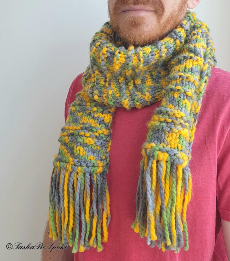 May include: A knitted scarf with yellow, green, and gray stripes and long fringe tassels.