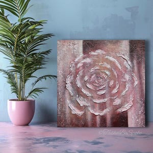 May include: Square canvas art with a textured, raised-relief rose in white and pink hues. The artwork is set against a backdrop of brown and pink vertical stripes. A potted palm plant in a pink pot is on the left.