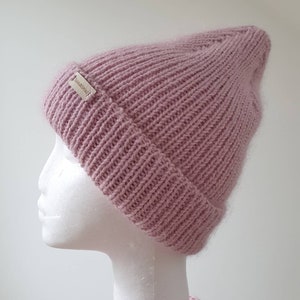 K&ouml;nnte beinhalten: Eine rosafarbene Strickm&uuml;tze mit einem kleinen Etikett mit der Aufschrift "TashaBeSpoke".