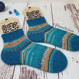 May include: Two pairs of teal, orange, and white striped socks with a wooden tag that says "Tasha Be Spoke" and "M".