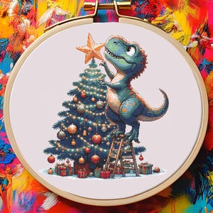 May include: A cross-stitch embroidery hoop featuring a cartoon dinosaur decorating a Christmas tree. The dinosaur, in shades of blue and green, stands on a small ladder, placing a star on top of the tree. The tree is adorned with ornaments and lights, surrounded by wrapped gifts.