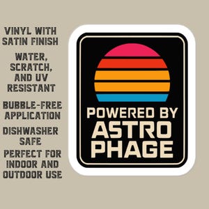 May include: A rectangular vinyl sticker with a black background featuring a stylized sunset graphic in pink, red, orange, and blue stripes above the text POWERED BY ASTRO PHAGE in white. The text to the left lists product features including vinyl with satin finish, water, scratch, and UV resistant, bubble-free application, dishwasher safe, and indoor and outdoor use.