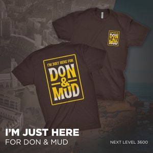Puede incluir: Una camiseta marrón con un gráfico amarillo que dice "I'm just here for Don & Mud". El gráfico está en un cuadro con un contorno blanco. La camiseta se muestra en un modelo.