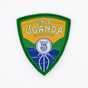 May include: A green, yellow, and blue embroidered patch with the text "Jinja Uganda The Pearl of Africa" and "Source of The Nile River".