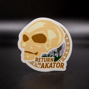 May include: A round sticker with a beige skull illustration and a green jungle scene. The text "RETURN TO AKATOR" is written in brown letters below the skull.