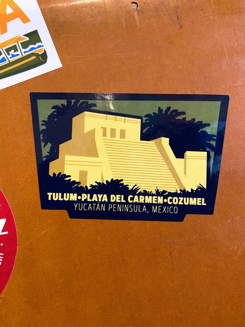May include: A green, yellow, and blue sticker with a stylized image of a Mayan temple with a text overlay that reads "TULUM.PLAYA DEL CARMEN.COZUMEL YUCATAN PENINSULA, MEXICO"