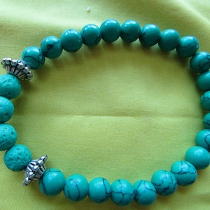 May include: A turquoise beaded bracelet with silver metal accents. The beads are round and have a slightly rough texture.
