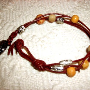 May include: A brown leather bracelet with multiple strands and wooden beads in shades of beige and brown.