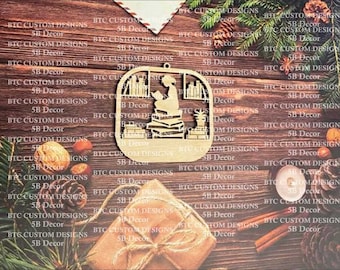 May include: A wooden ornament featuring a silhouette of a person sitting in a chair surrounded by books. The ornament is painted in a light brown color and has a cutout design.