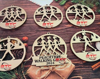 Könnte beinhalten: Sechs runde Holzornamente mit Silhouetten von Personen, die gehen. Die Ornamente sind aus braunem Holz gefertigt. Auf einem der Ornamente steht der Text "Peachtree Walking Group 2024".